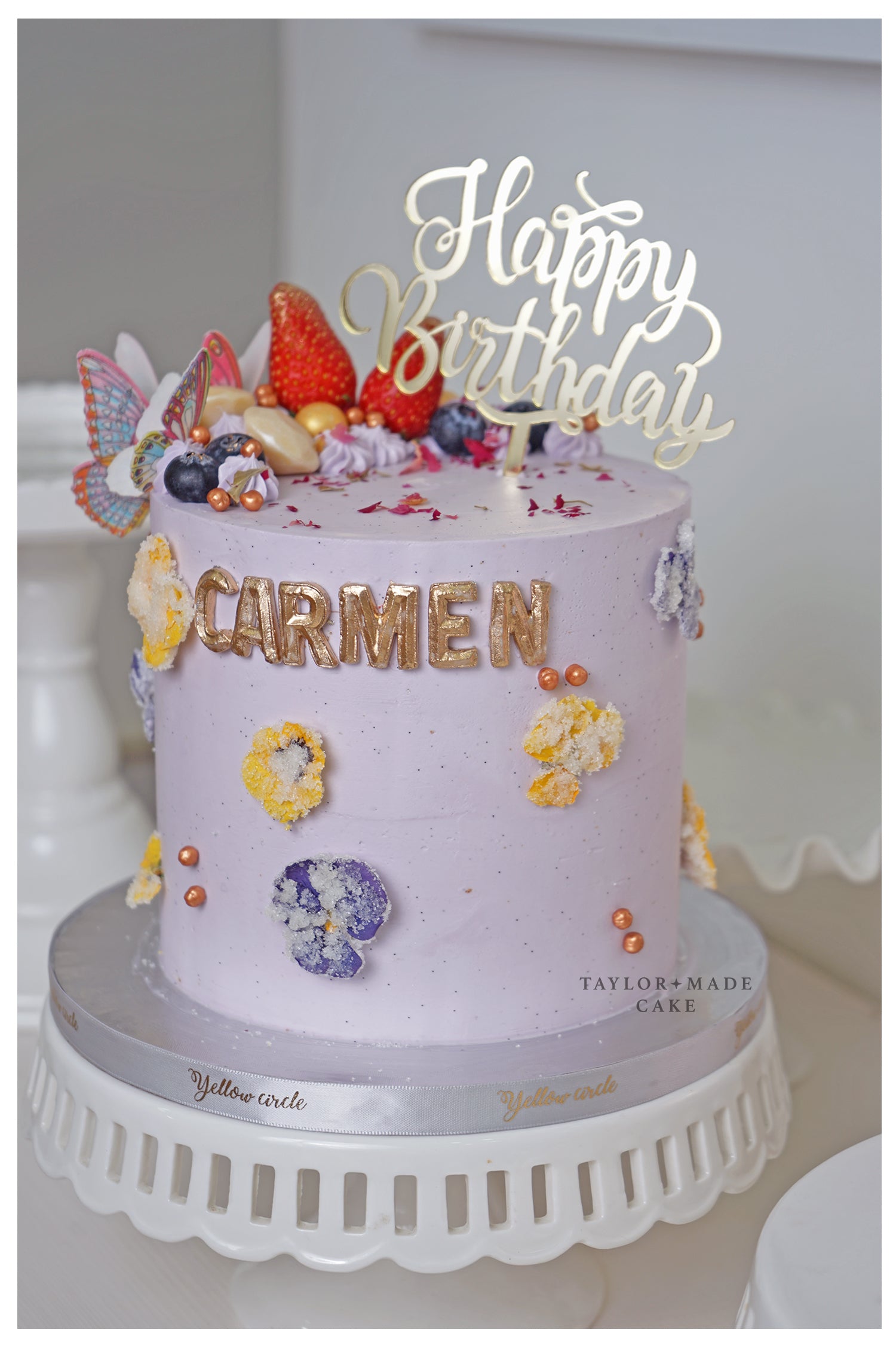 Decorative birthday cake with 'Happy Birthday Carmen' on a white background